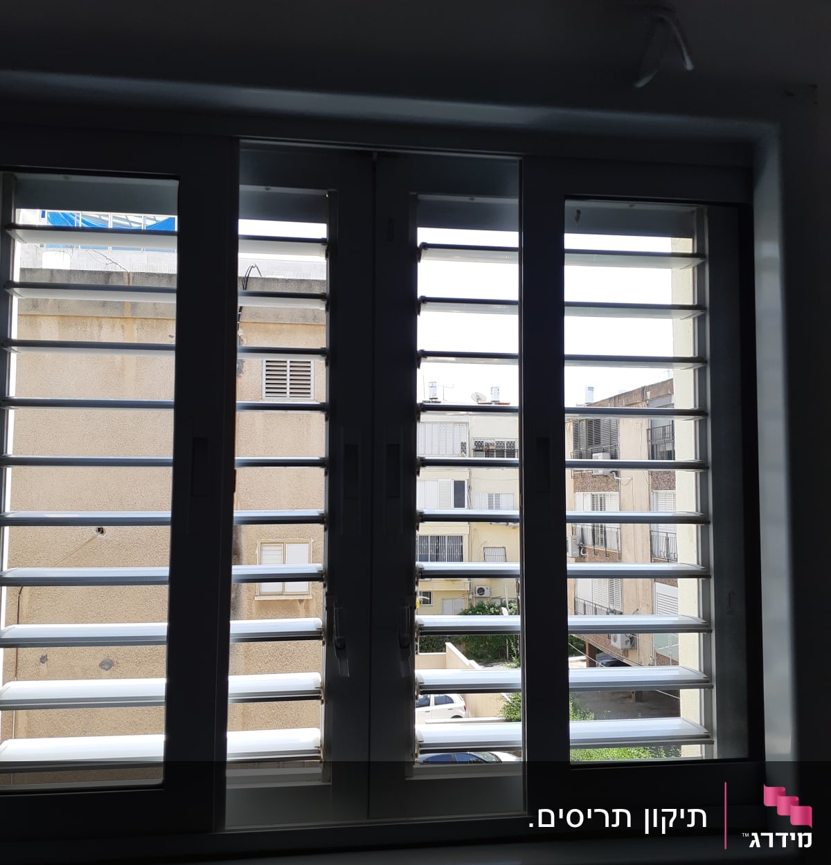 תריסים לבנים פתוחים עם נוף בניינים ברקע